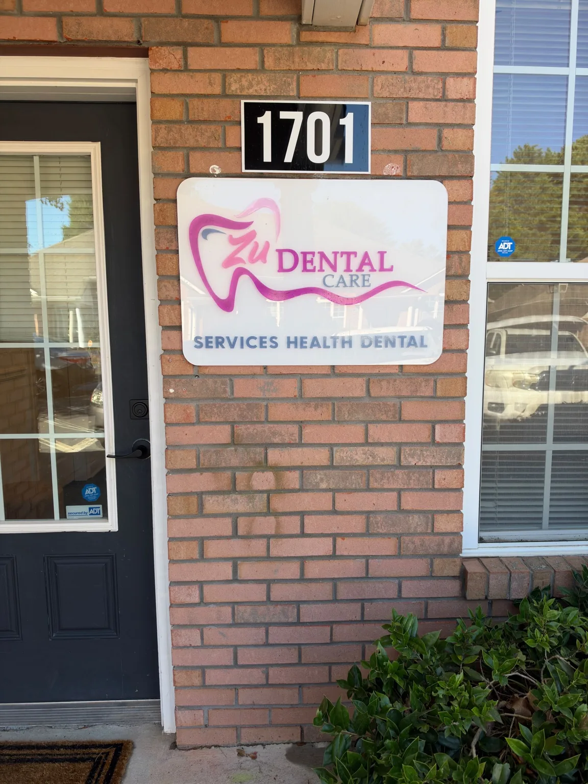 La entrada de Zu Dental Care, con su logo rosa y el número 1701 sobre el letrero.
